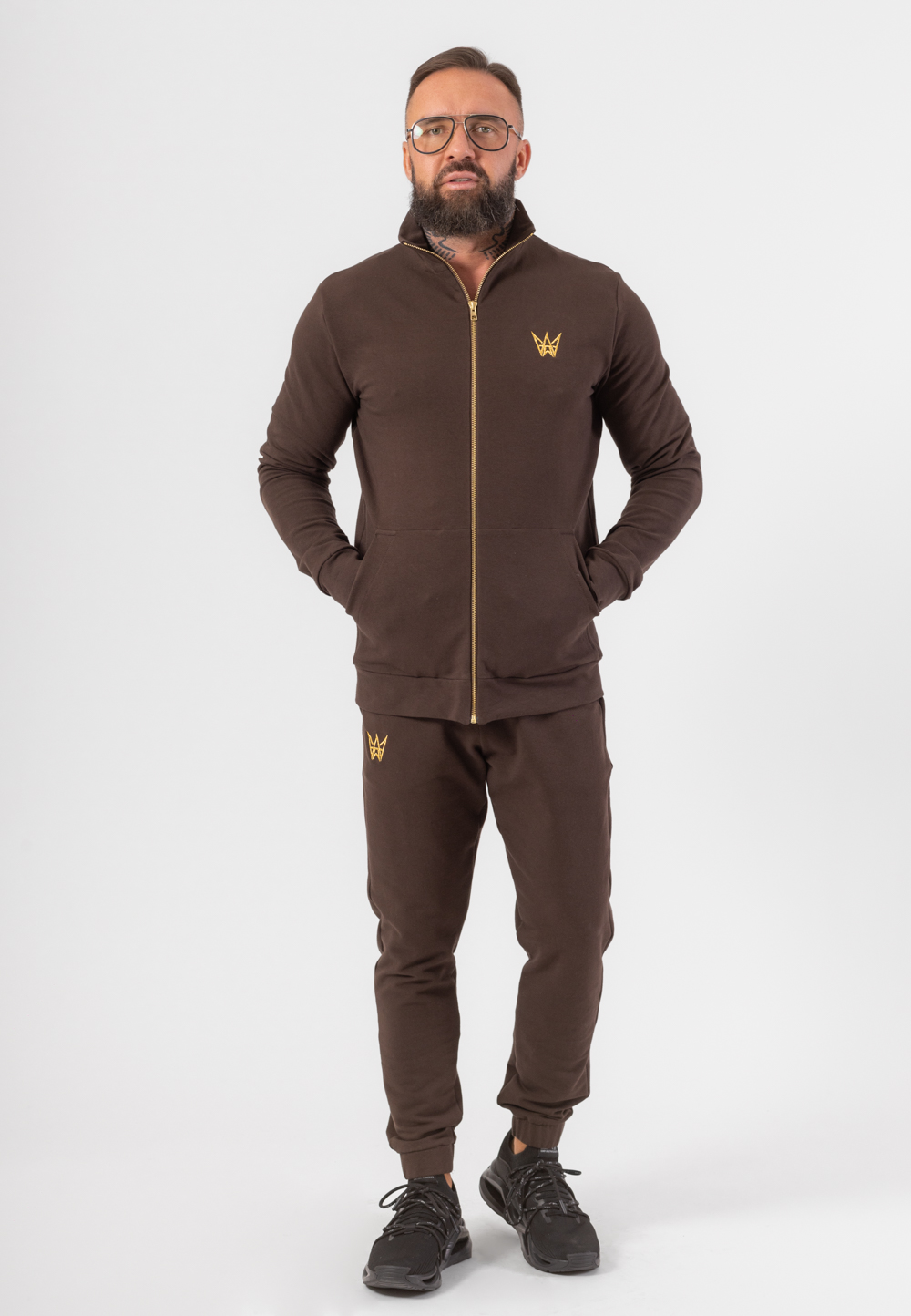 Komplet dresowy składający się z bluzy z golfem rozpinanej na zamek i długich spodni w kolorze czekoladowym z haftowaną koroną w kolorze złotym.